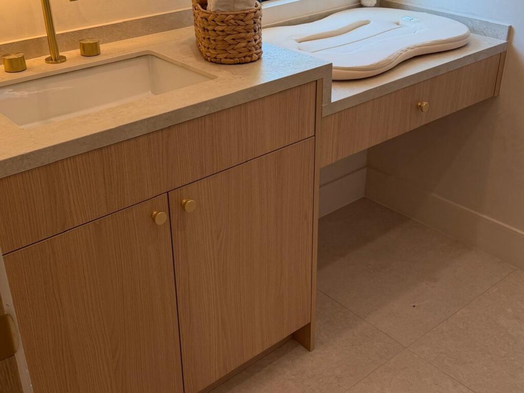 White oak bathroom vanity with a stone counter and gold fixtures