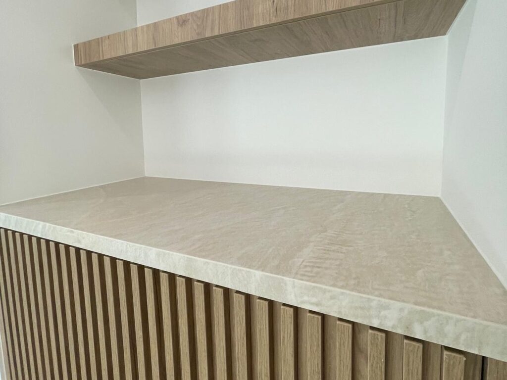 Fluted white oak cabinet with floating oak shelves and a travertine top