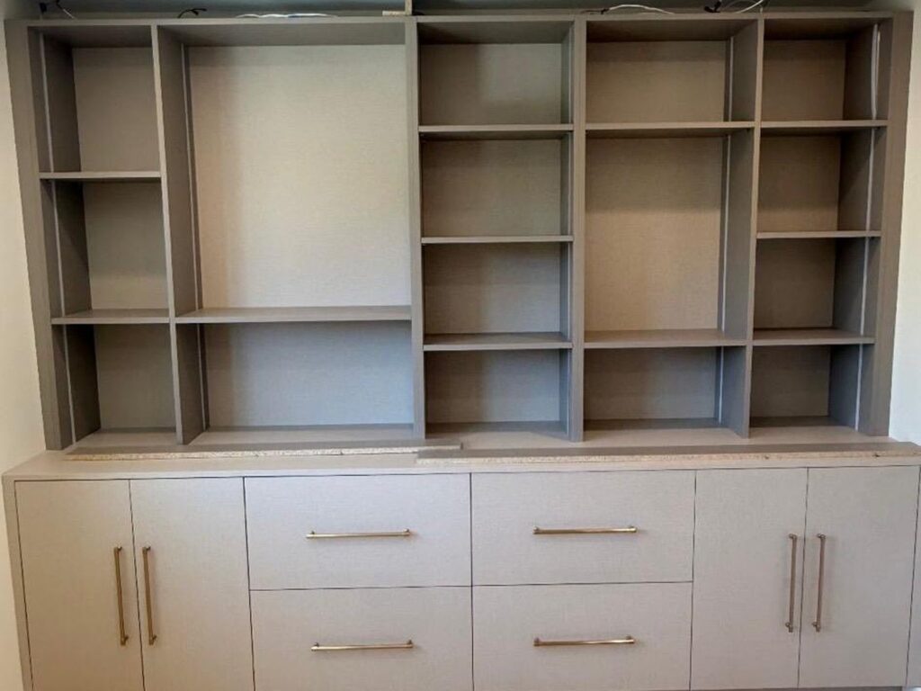 Custom built-in shelving and media cabinet in warm gray