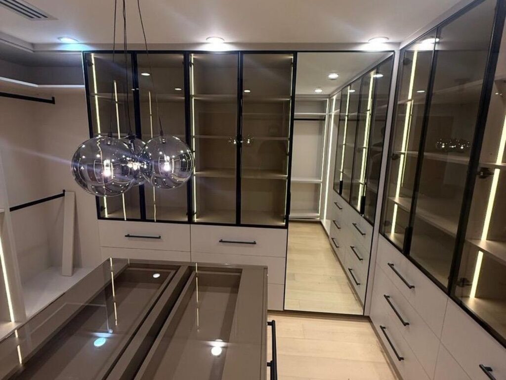 Custom walk-in closet with glass-front, lit display cabinetry