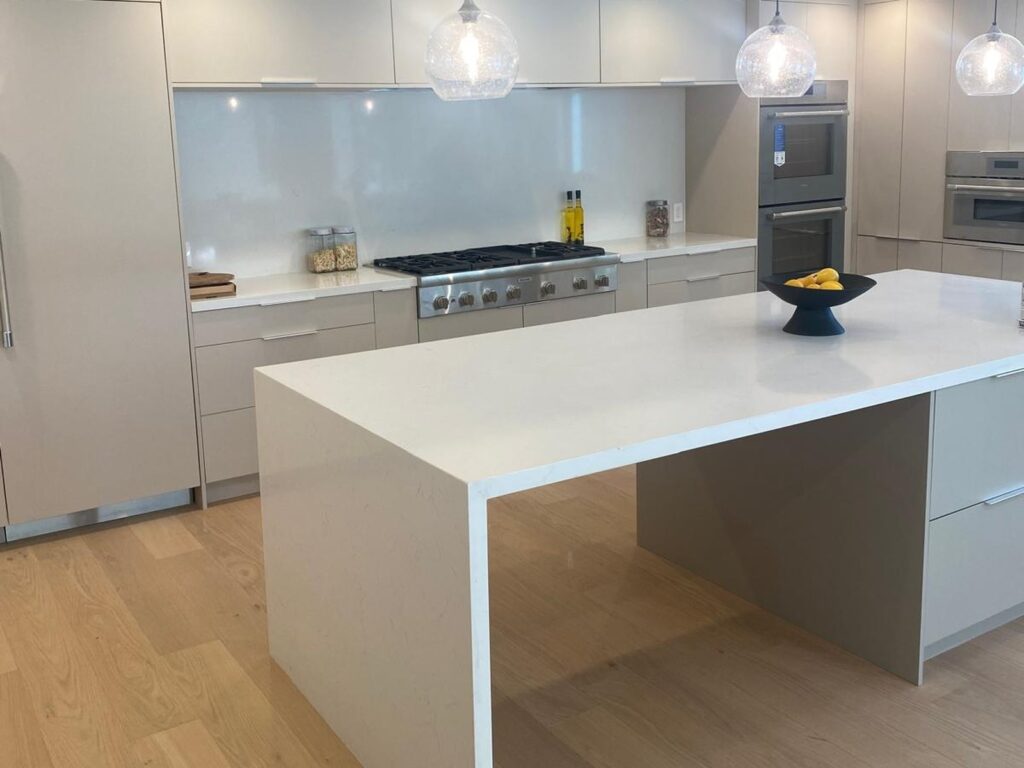 Modern gray kitchen with a quartz island, gas range, and double wall ovens