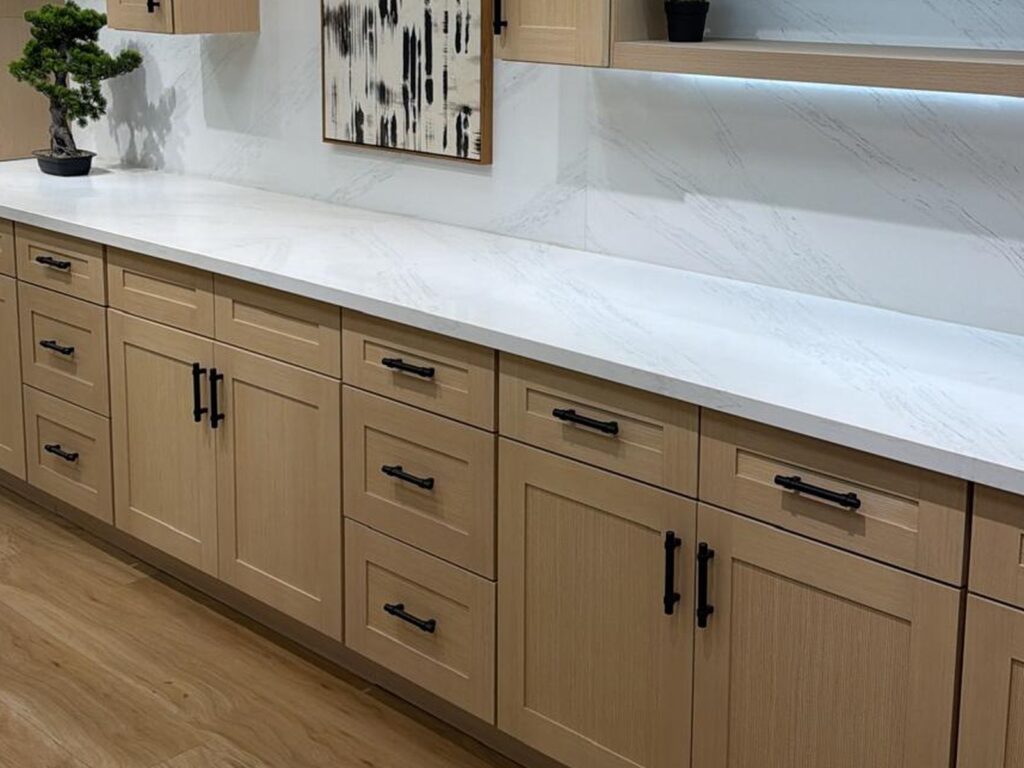 Light oak shaker cabinets with a white marble countertop and black hardware