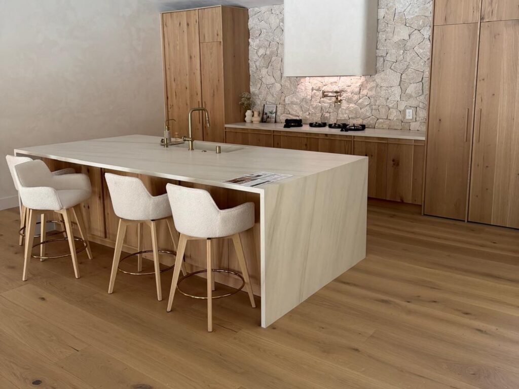 White oak kitchen with a natural stone backsplash and a waterfall island with boucle stools