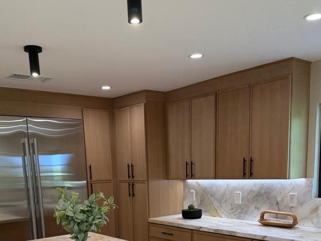 White oak upper cabinets with a marble backsplash and paneled refrigerator